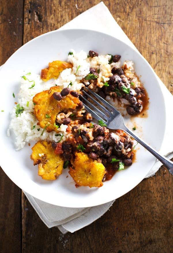 Garlic tostones on a white plate with rice and beans.