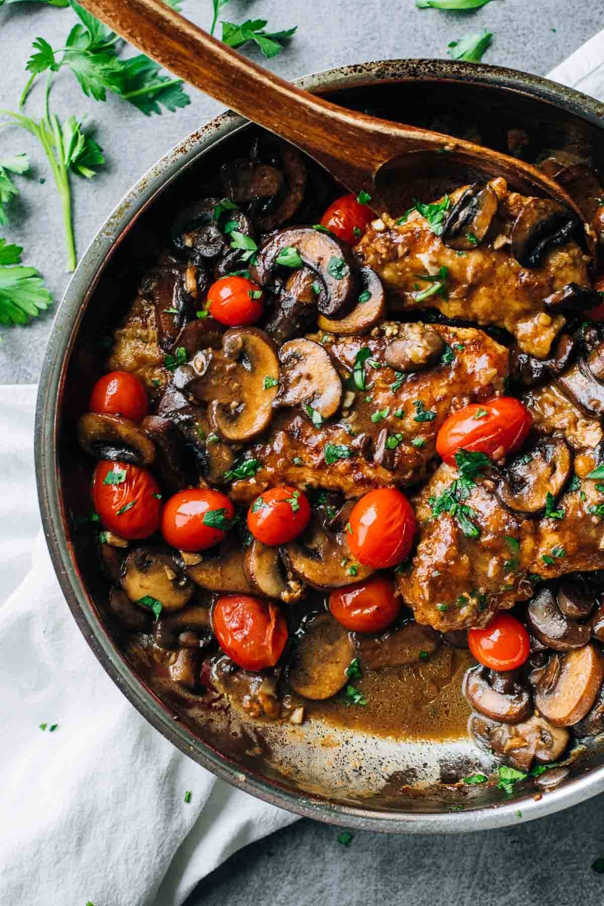Chicken Marsala in a skillet with a wooden spoon.